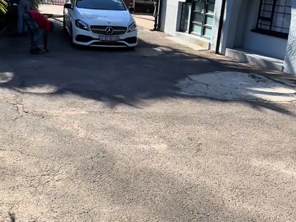 Resurfaced driveway at a white home with a car parked on it