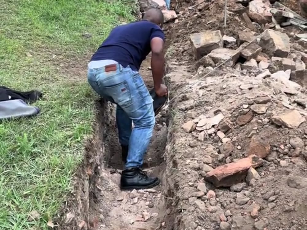 Crew excavating a retaining wall foundation trench on a slope